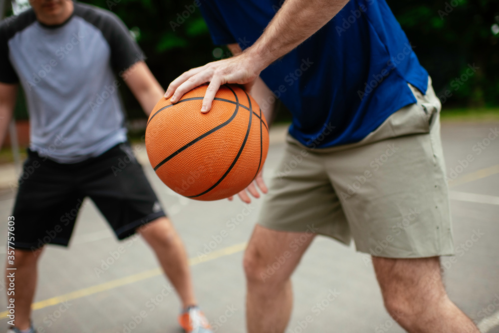 Close up of hands holding ball. Friends playing basketball in the park.