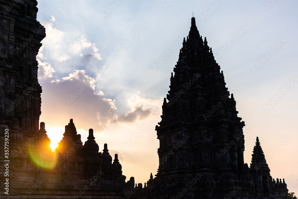 Silhouette of Prambanan hindu temples at sunset time. Bright sun glare and rays behind the buildings silhouette. The largest Hindu temple site in Indonesia. Yogyakarta, Java, Indonesia, Southeast Asia