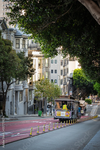 Tourists and local people ride Cable Car Trolley going down hill middle of the street. Fun traditional culture of public transportation in the city of San Francisco in California.