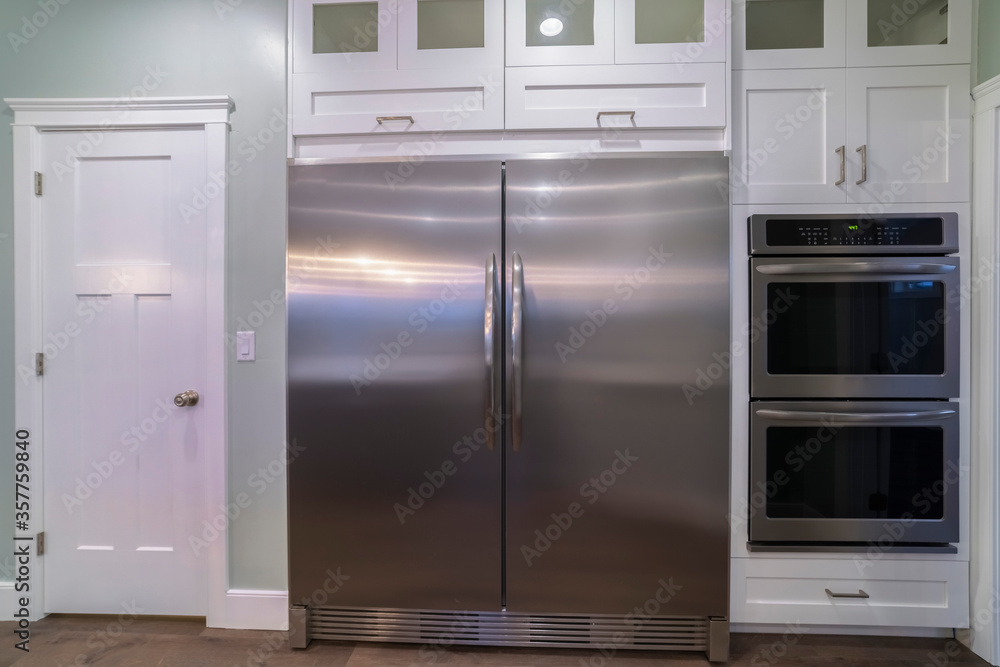 Large double door fridge with fitted ovens Stock Photo | Adobe Stock