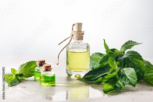 Peppermint essential oil and fresh mint leaves.