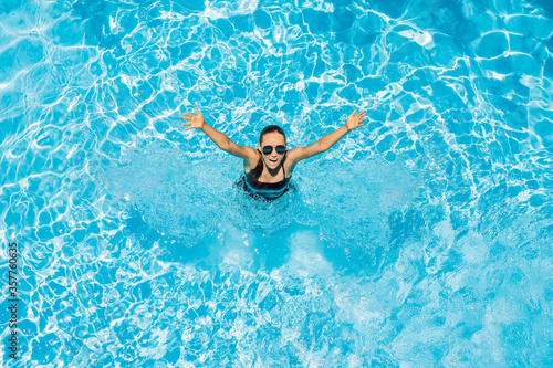 Woman in sunglasses swims in the pool