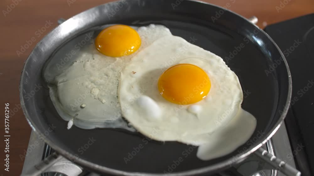 chef cracking egg in hot pan for cooking. Fried egg in iron pan. chef cracking egg in hot pan for cooking. Fried egg in iron pan.