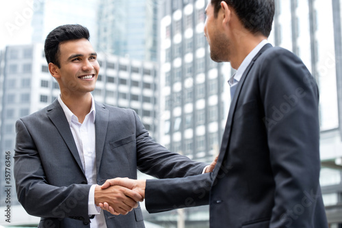 Fotografie Young handsome Indian businessman make a handshake with partner in the city
