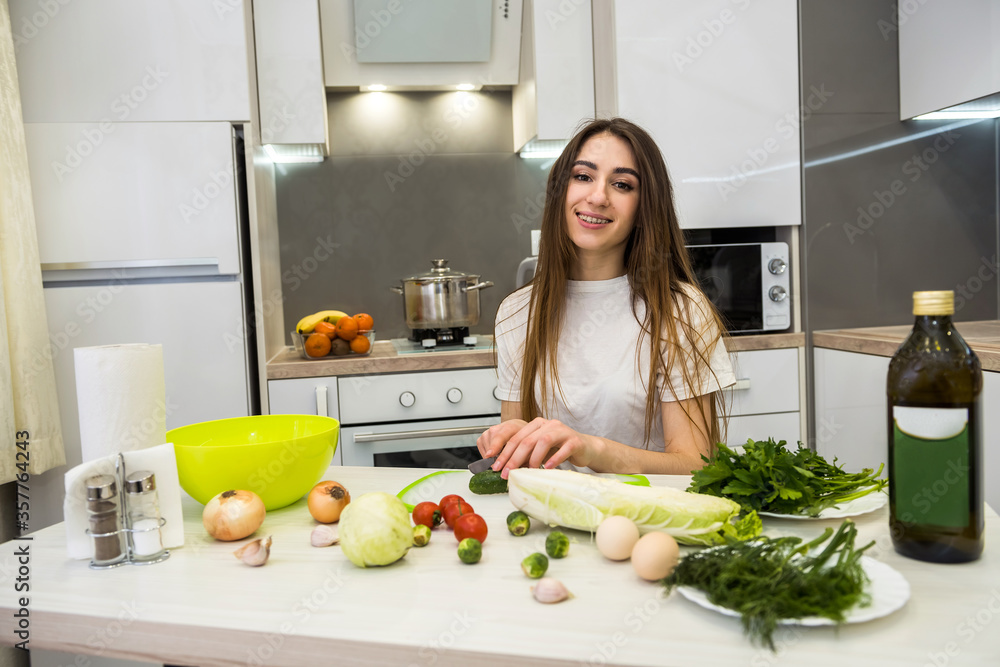 charming girl prepares a salad of different vegetables and greens flavored with olive oil for a healthy lifestyle.