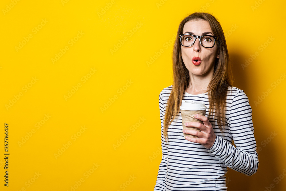 Young woman surprised in glasses with a coffee on a yellow background Young woman surprised in glasses with a coffee on a yellow background