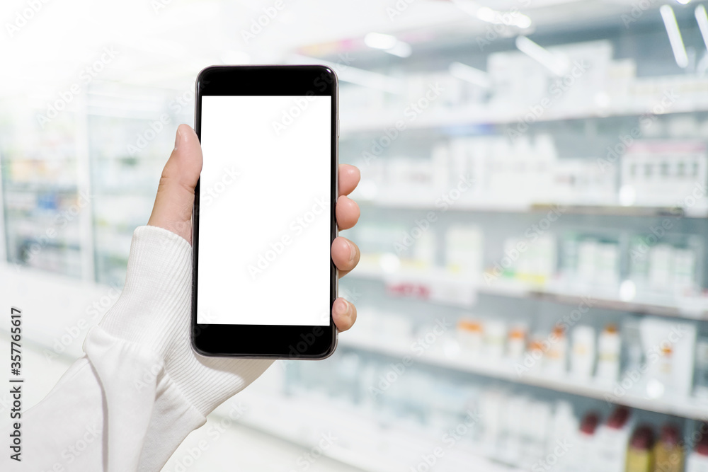 Hand holding mobile smartphone in drug store to compare price of medicine