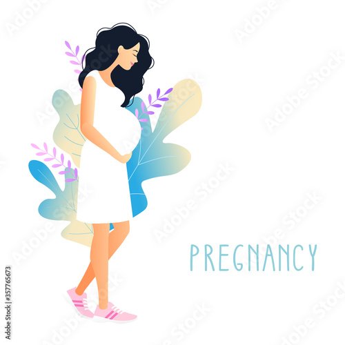 beautiful pregnant woman with hand on her stomach on a background of foliage. young woman stroking belly. Pregnancy.