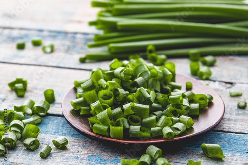 Fresh green onion chopped and lies on a bowl on a background of blue boards.