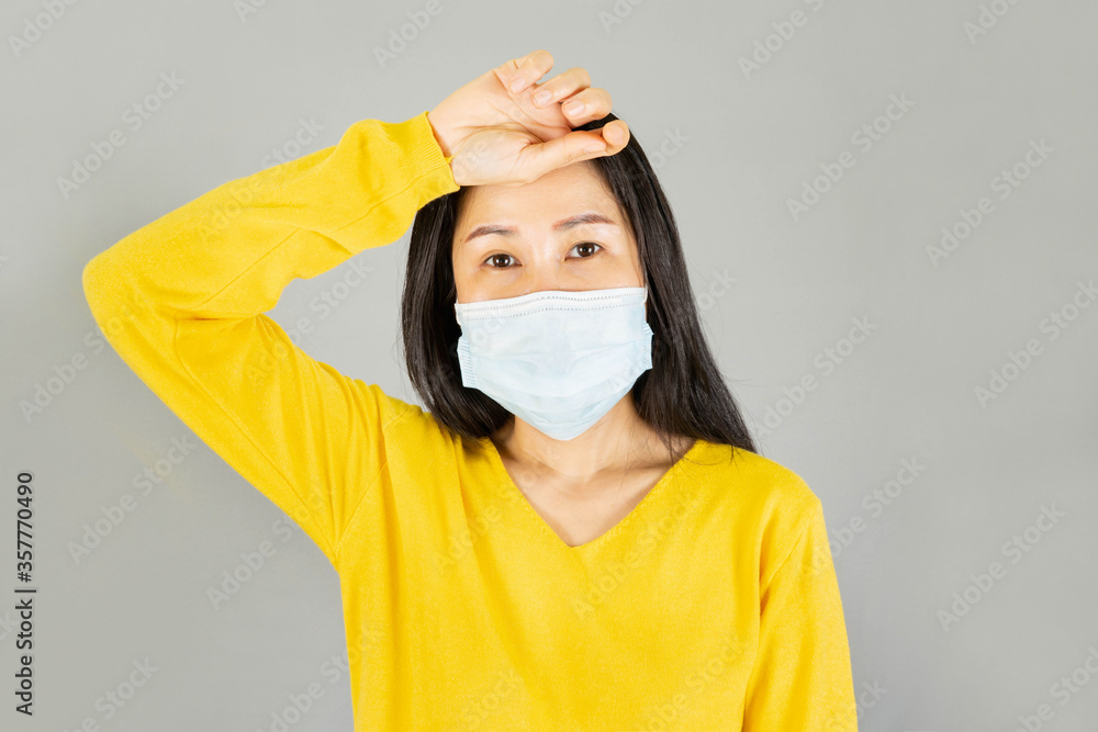Headache,Young asian woman in yellow shirt wearing medical face mask, isolated on white background,health care concept Headache,Young asian woman in yellow shirt wearing medical face mask, isolated on white background,health care concept