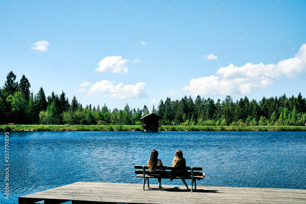 Zwei Frauen am See genießen den Sommer auf dem Steg 