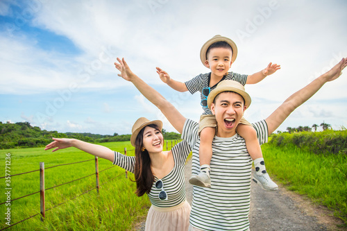  happy father giving son piggyback ride on his shoulders and walking on country road