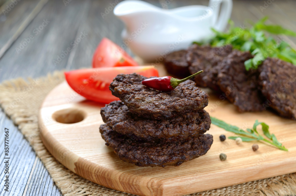 Tasty homemade liver cutlets stacked on a wooden board. Selective focus