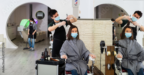 Man doing haircut for woman in salon using face masks