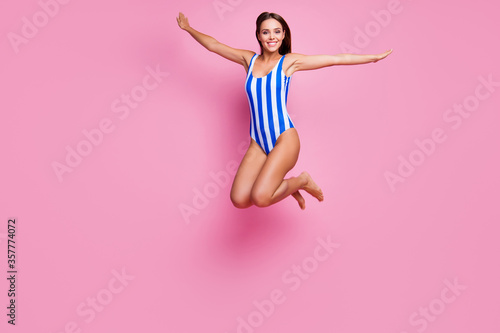 Full body photo of crazy hot figure lady fit legs long straight hairdo jump high into sea ocean water spread arms like wings wear striped bodysuit isolated pastel pink color background