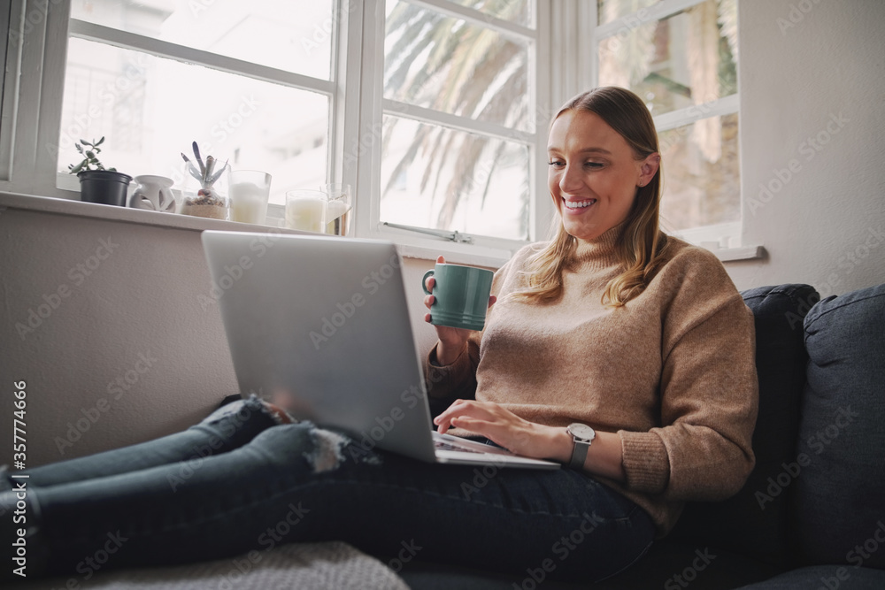 Self isolated businesswoman working on laptop computer sitting at home holding a coffee cup in hand during quarantine during covid-19 and coronavirus epidemic Self isolated businesswoman working on laptop computer sitting at home holding a coffee cup in hand during quarantine during covid-19 and coronavirus epidemic