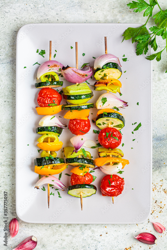 Fototapeta Grilled vegetable skewers on gray rectangular plate, top view. Vegan food concept.