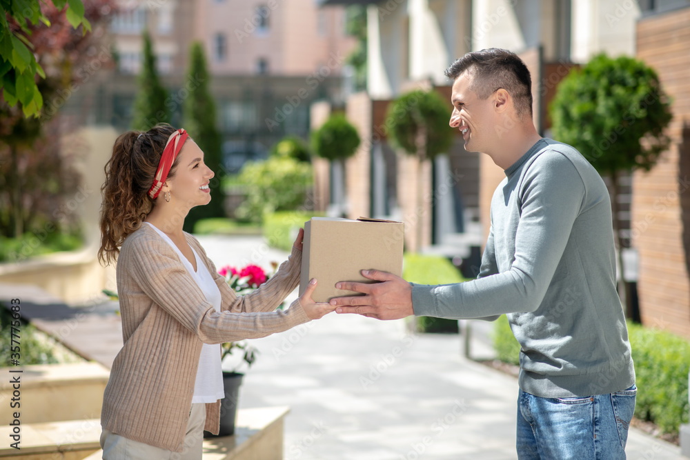 Smiling woman passing a box to her husband Smiling woman passing a box to her husband