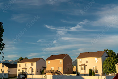 Suburb homes with gable roofs against mountain peak and blue sky with clouds