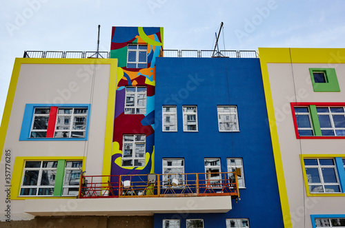 The progress of construction of the kindergarten building. Modern decoration of building facades.Hanging scaffolding platform or window cleaning cradle system at construction site