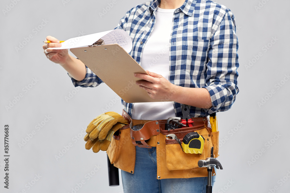 repair, construction and building concept - woman or builder with clipboard, pencil and working tools on belt over grey background repair, construction and building concept - woman or builder with clipboard, pencil and working tools on belt over grey background