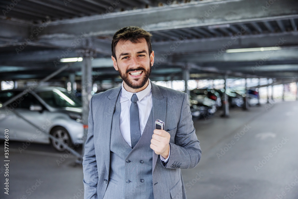 Fototapeta premium Young smiling handsome man in suit just bought a car and holding his keys.