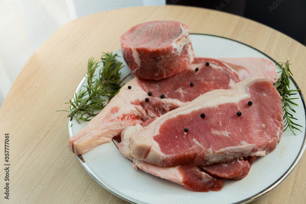 Mix of raw beefsteak tomahawk rib-eye tenderloin and strip loin with herb on wooden background Mix of raw beefsteak tomahawk rib-eye tenderloin and strip loin with herb on wooden background