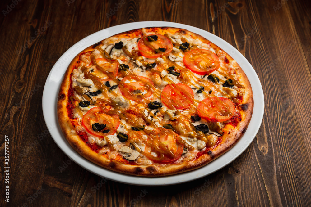 Pizza with chicken meat, mushrooms, tomatos and black olives, wooden background, low key