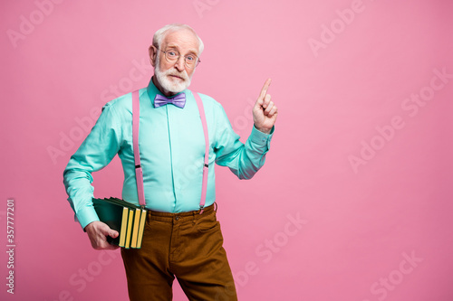 Photo of funny aged grandpa teacher hold books lecturer university college direct finger empty space black board wear specs shirt suspenders bow tie pants isolated pink pastel color background