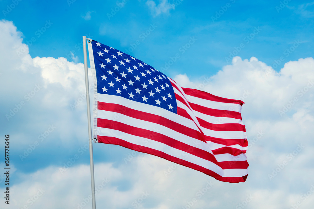 Obraz premium America flag blowing in the wind under blue sky