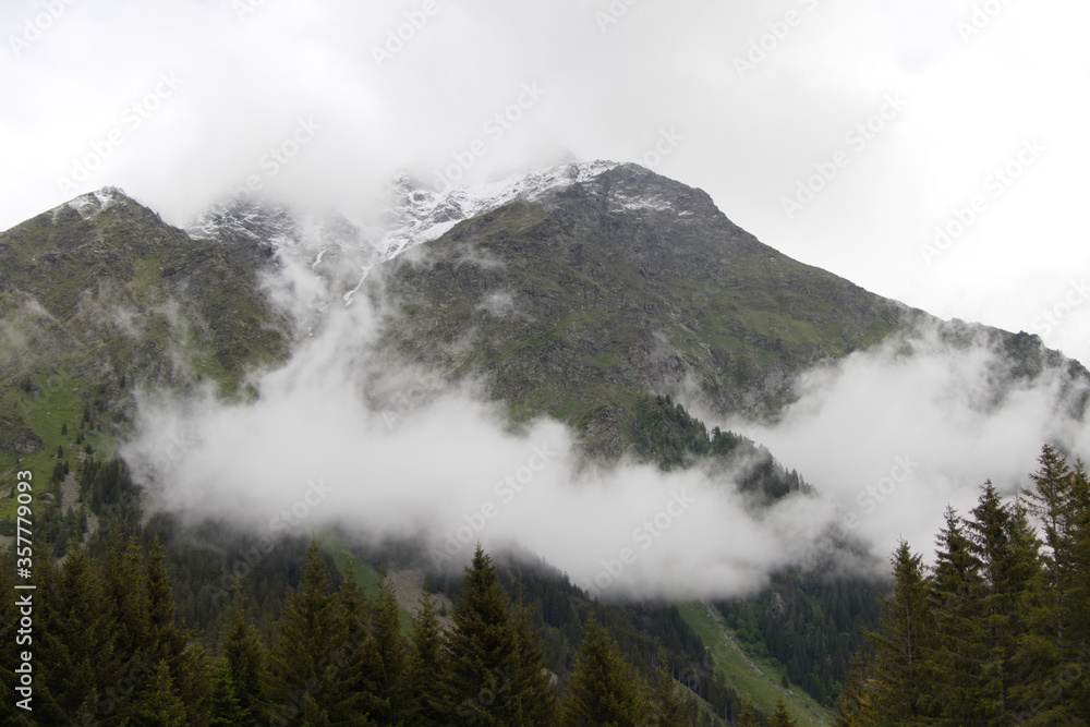Cloudy peaks and shreds of fog in wild nature near the San Bernardino Pass in the European Alps