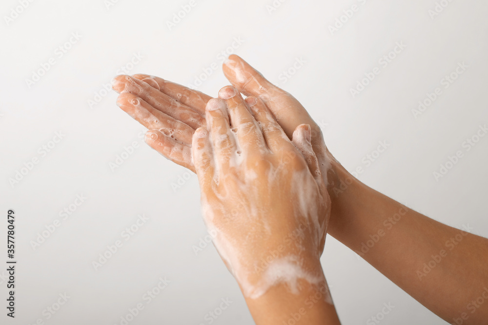 Fototapeta premium Child hands in soap bubbles against a grey wall. Concept of washing hands