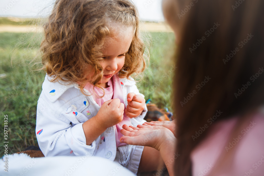 Blonde mother with two cute daughters are walking and having fun outdoors. Stylish, casual clothes. Blonde mother with two cute daughters are walking and having fun outdoors. Stylish, casual clothes.