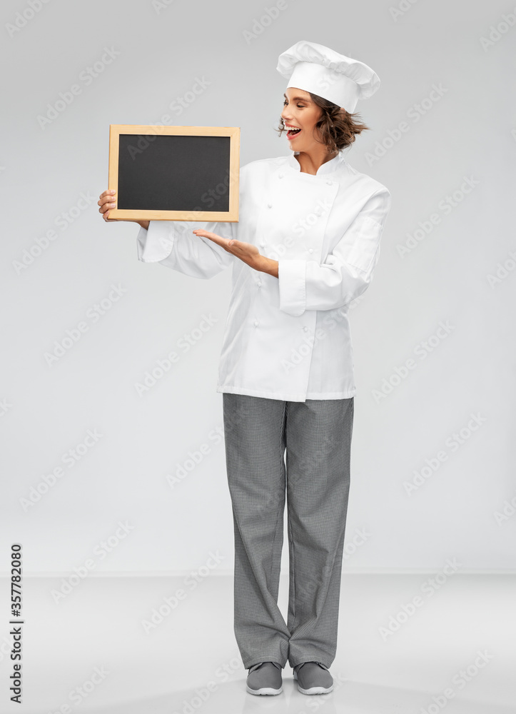 cooking, advertisement and people concept - happy smiling female chef holding black chalkboard over grey background cooking, advertisement and people concept - happy smiling female chef holding black chalkboard over grey background
