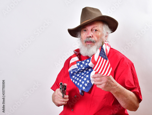 Texas rancher wearing a patriotic bandana and ready to defend his propery..Old man with a floppy western hat and a six shooter. photo