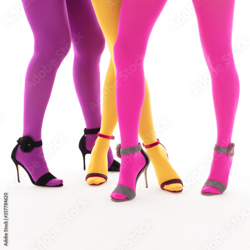 Beautiful luxurious female models in bright colored tights, on their feet various sandals with high heels of different colors on a white background, shoe advertising, banner, mock-up