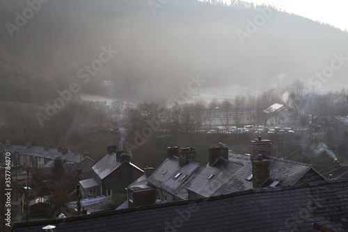 A smoky, misty view across slate rooftops in a Welsh village in Winter.