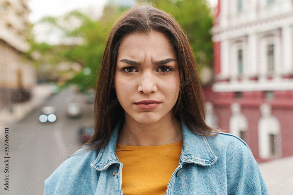 Image of attractive displeased woman looking at camera while posing