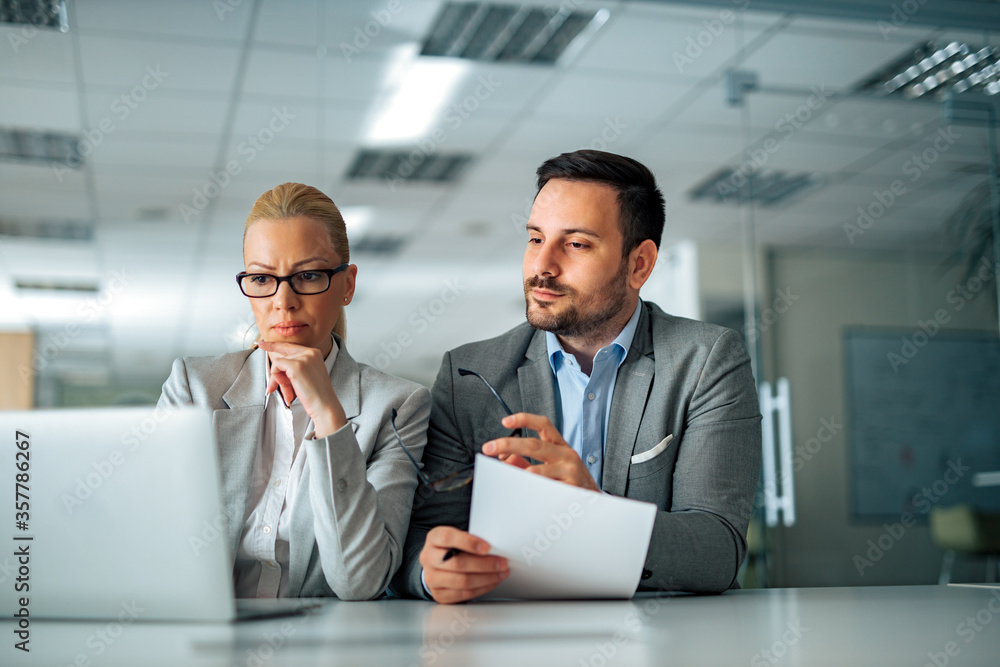 Two serious business managers working in the office, portrait. Two serious business managers working in the office, portrait.