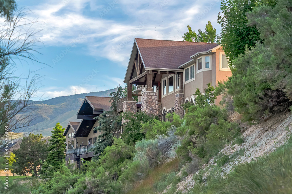 Homes on hilly terrain with mountain and cloudy blue sky in the background Homes on hilly terrain with mountain and cloudy blue sky in the background
