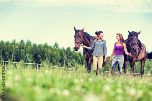 Young girls riding horses bareback in field
