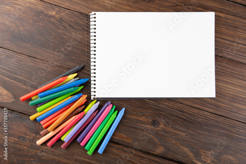 colored crayons and blank page on the wooden table