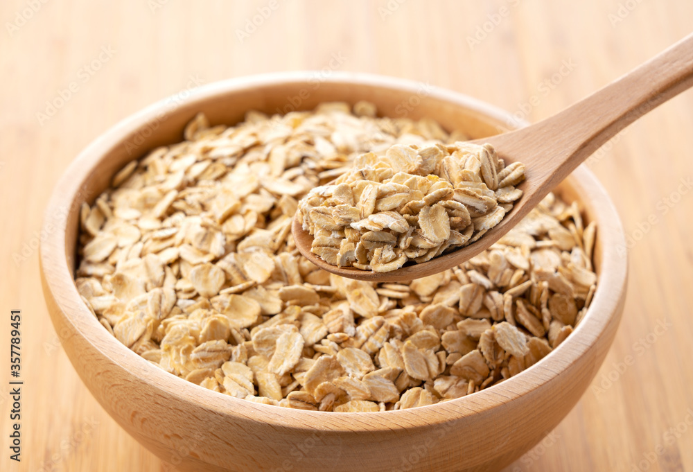 Oatmeal and wooden spoon set against a wooden background Oatmeal and wooden spoon set against a wooden background