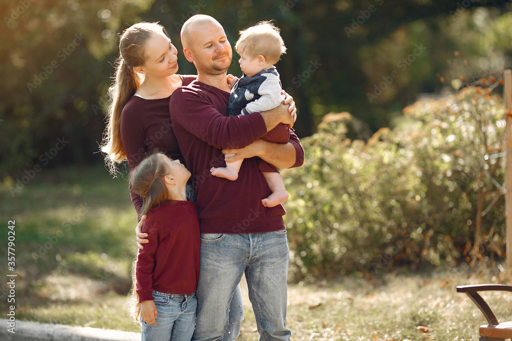 Family in a autumn park. Woman in a red sweater. Cute childrens with parents Family in a autumn park. Woman in a red sweater. Cute childrens with parents