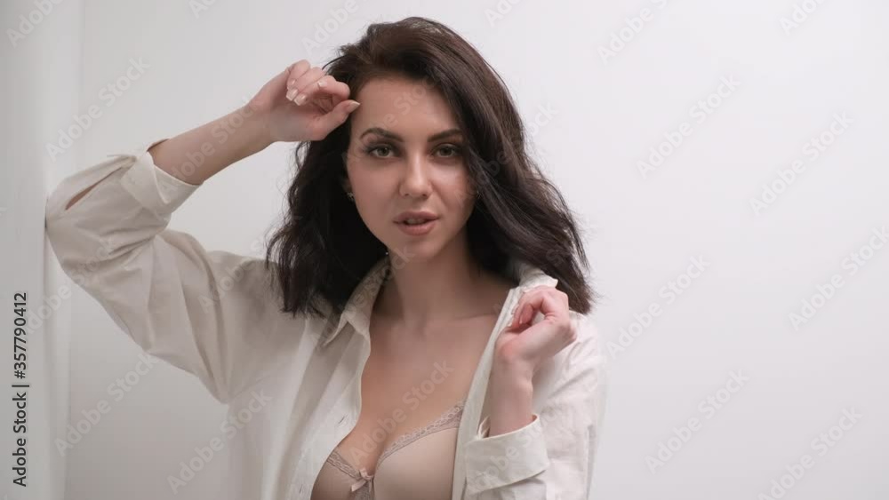 Beautiful sexy curly brown haired girl in bra, white shirt and jeans. Studio portrait on a white background. Beautiful sexy curly brown haired girl in bra, white shirt and jeans. Studio portrait on a white background.