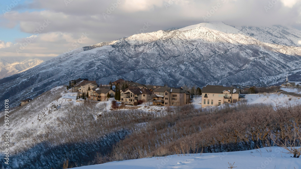 Panorama Pristine landscape of Wasatch Mountains with houses on its snow covered terrain