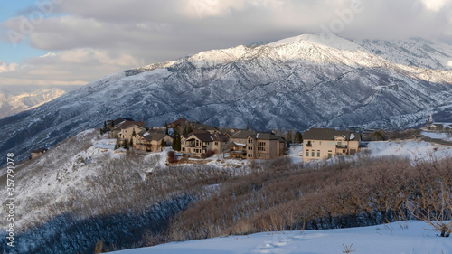 Panorama Pristine landscape of Wasatch Mountains with houses on its snow covered terrain