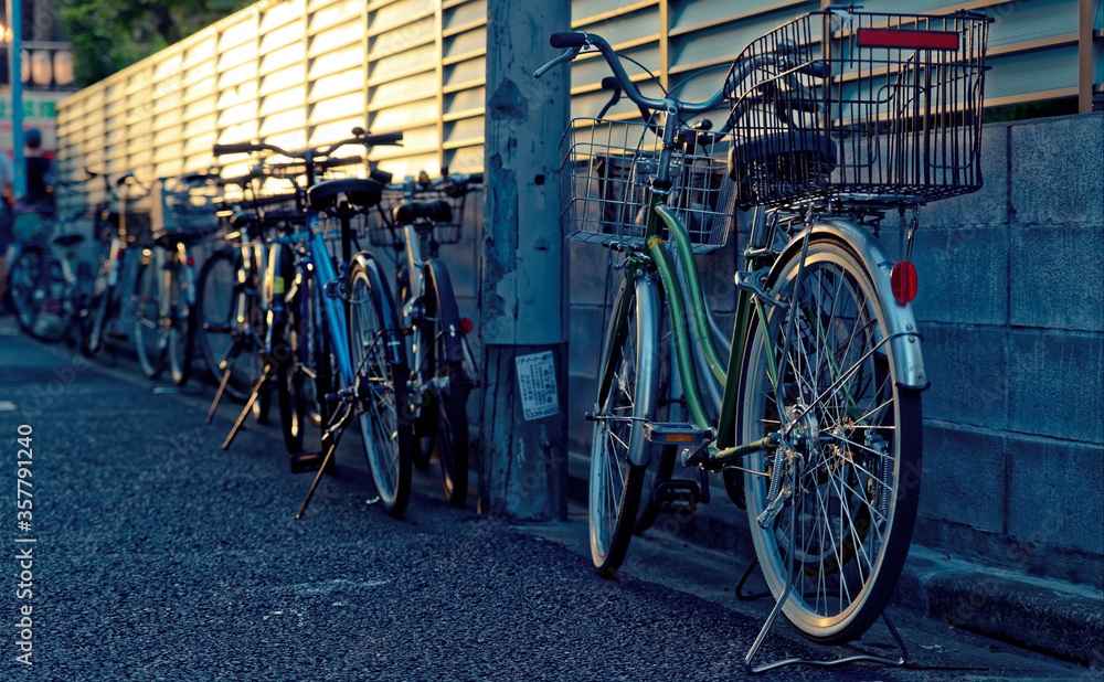 Row of bicycles parked along a wall in an urban alley in the late afternoon