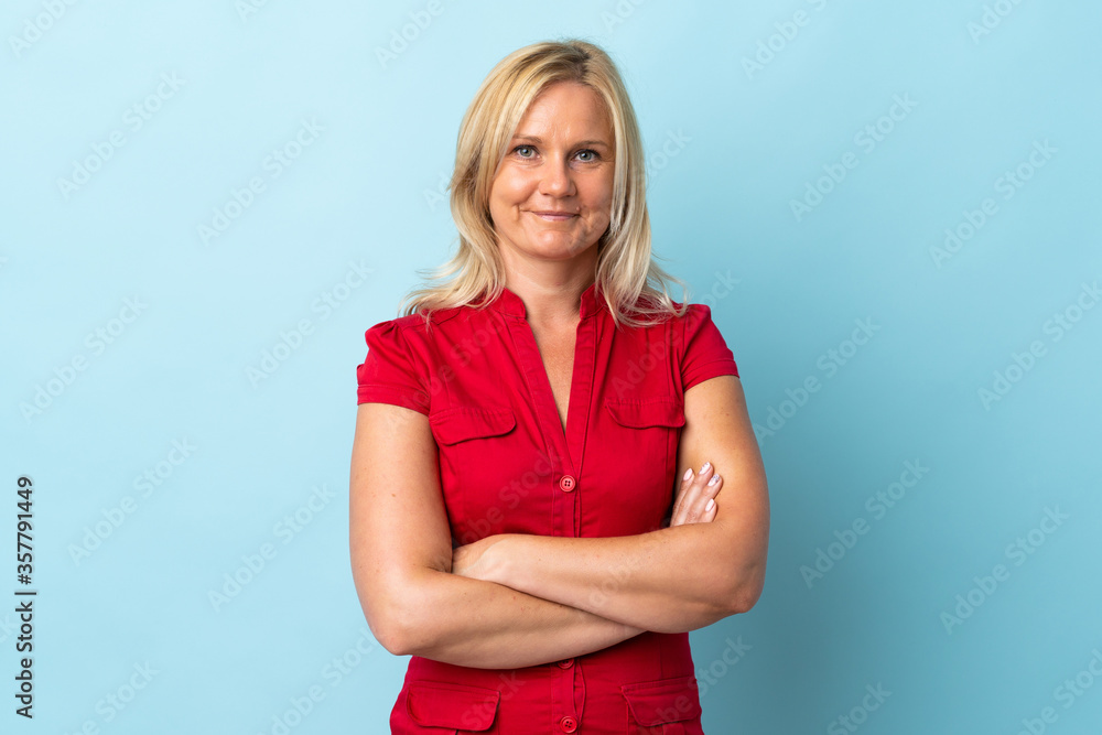 Middle age woman isolated on blue background keeping the arms crossed in frontal position Middle age woman isolated on blue background keeping the arms crossed in frontal position