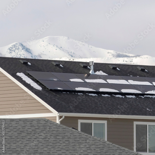 Square Exterior of homes with solar panels on gray roof against snowy Wasatch Mountain